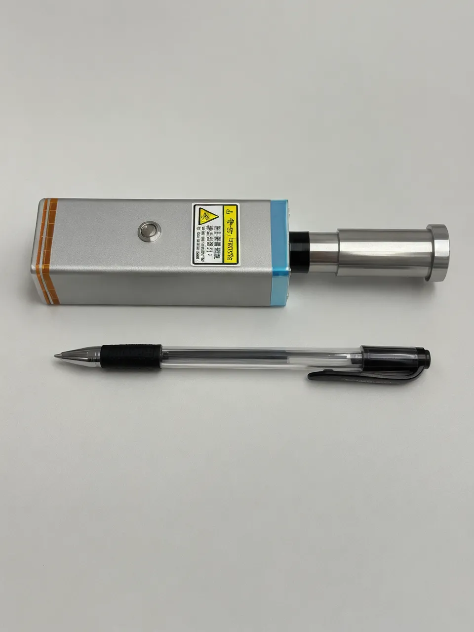 KyberSpark Core V2 lying on its side next to a standard ballpoint pen on a flat neutral surface, scale comparison showing the 160 mm length in context