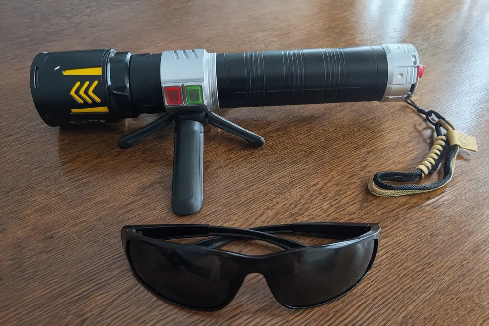 KyberSpark X and protective goggles laid flat together on a table, both clearly visible, showing the goggles as an included item alongside the device