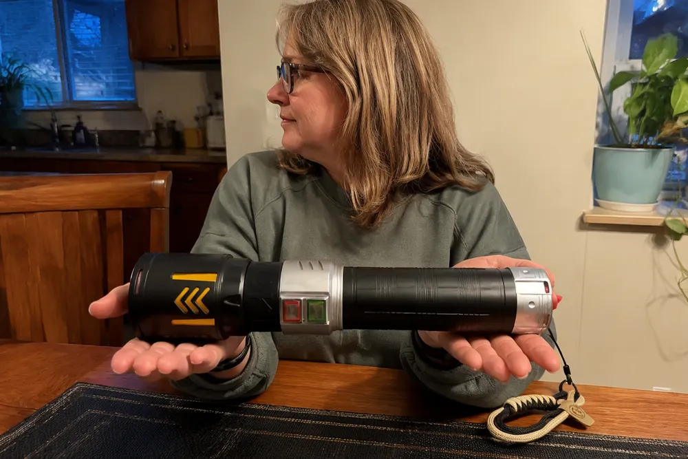 KyberSpark X held in one hand next to a common household ruler, clearly showing the 30 cm length and 7 cm diameter form factor for scale reference